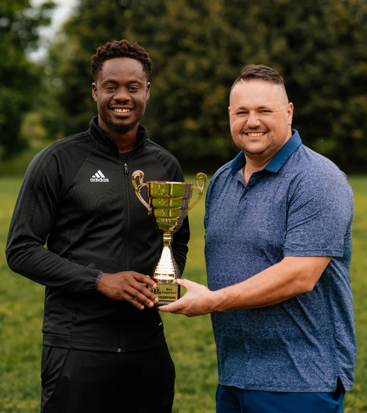 President Efosa Ogbeifun, left, and Club Administrator Michel Amorim, right, holding the 2026 MC4 championship trophy